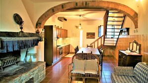 Un intérieur chaleureux avec une cheminée en pierre, un coin repas et une cuisine dotée de meubles en bois.
