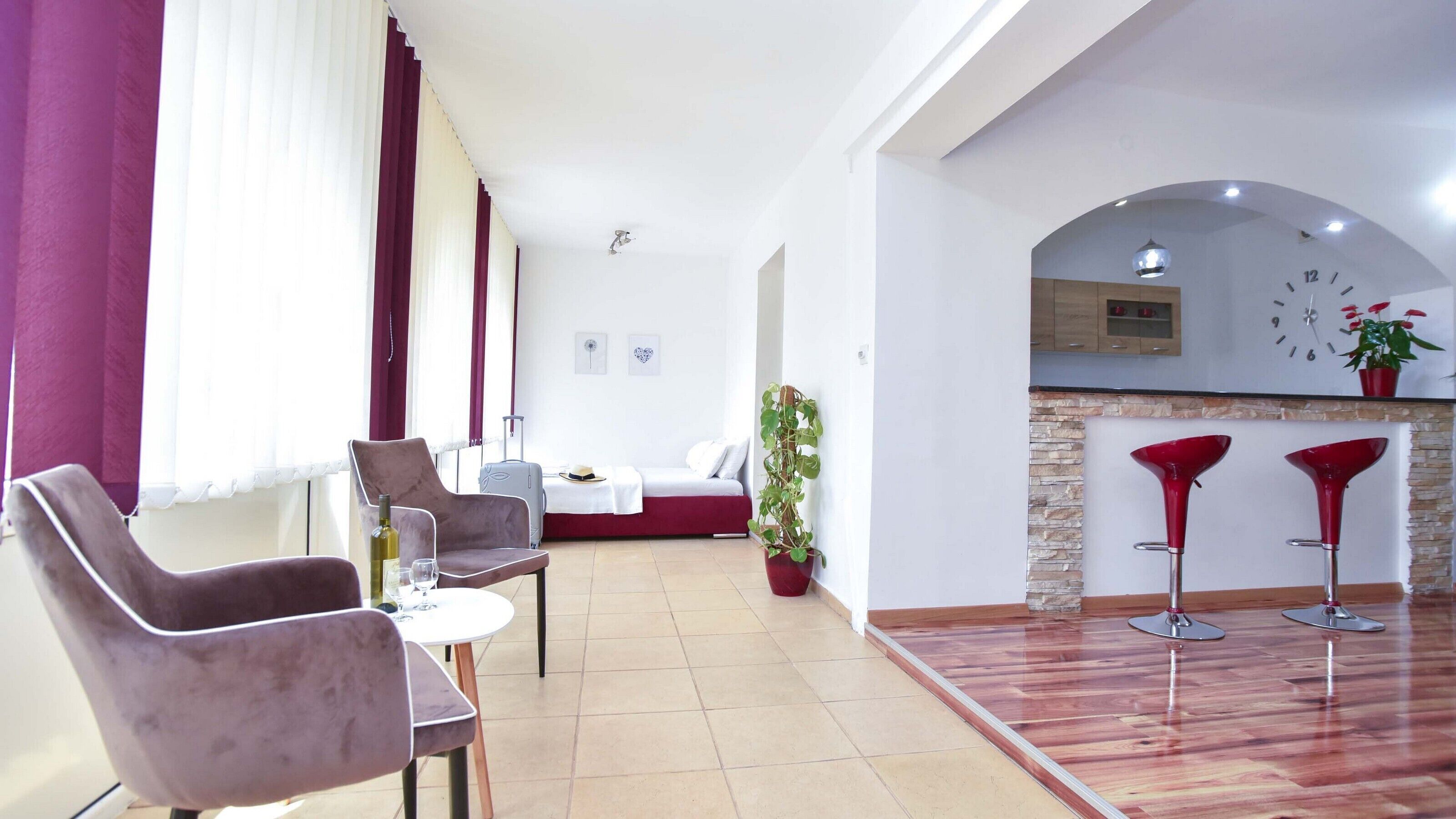 Un salon moderne comprenant un coin repas, une cuisine avec un mur arrière en pierre et un mur d’accent rouge.