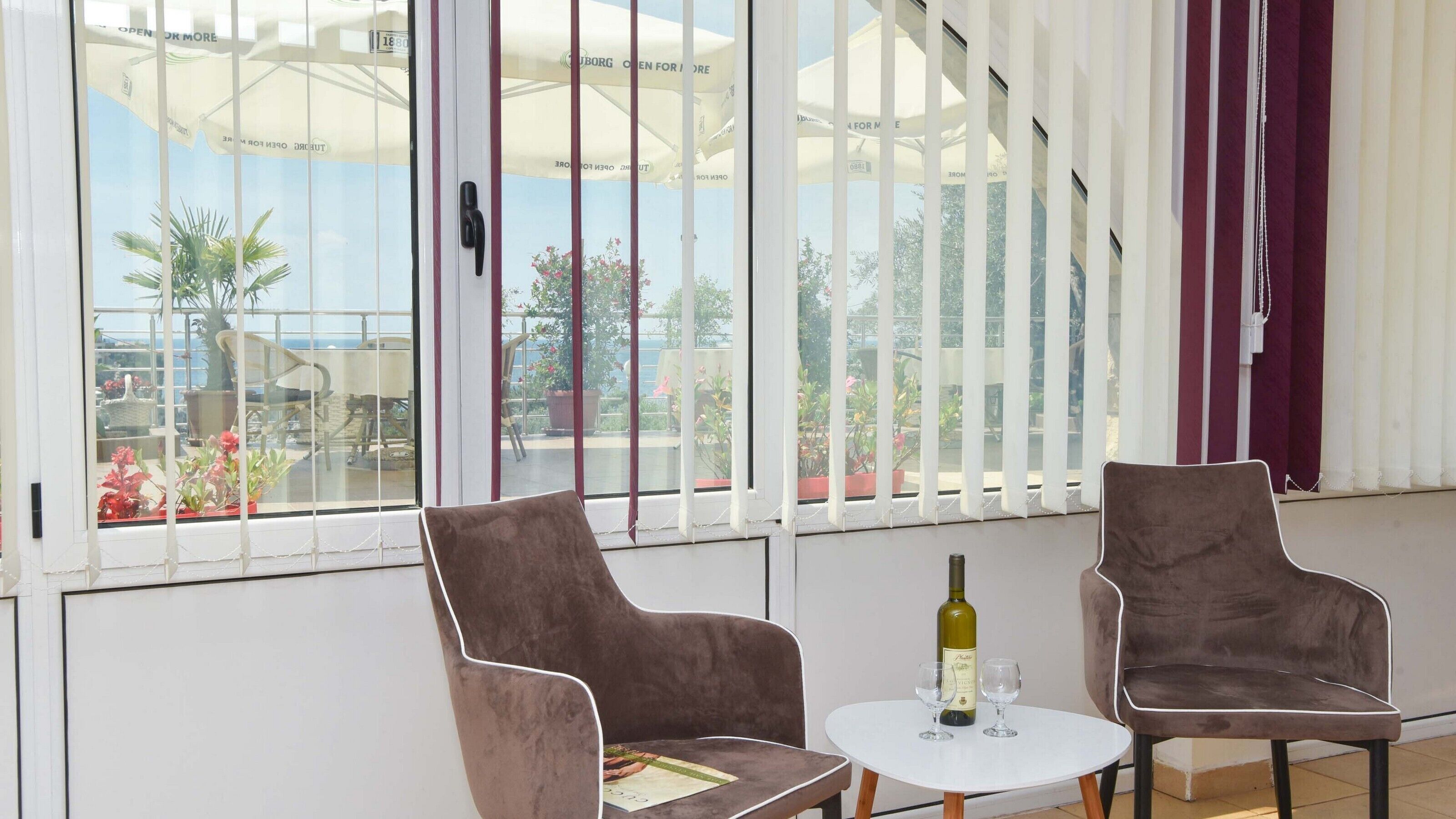 A room with two chairs, a small table, and a bottle of wine.