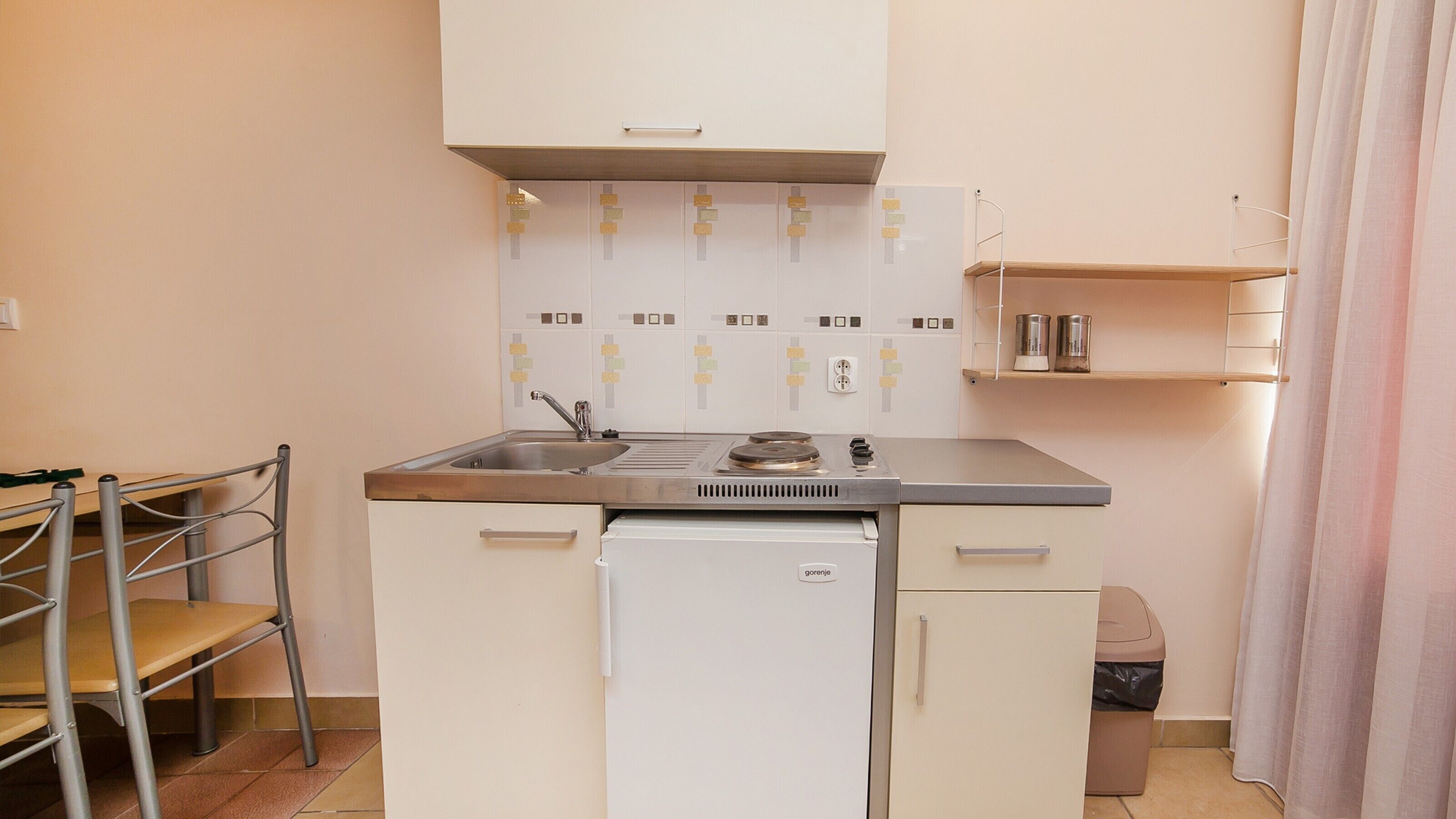 A compact kitchenette with a sink, stove, and storage cabinets.