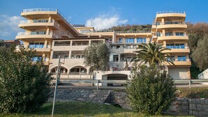 A multi-story hotel with balconies, a stone facade, and a palm tree in the foreground. - Apartments Raymond (Pržno)