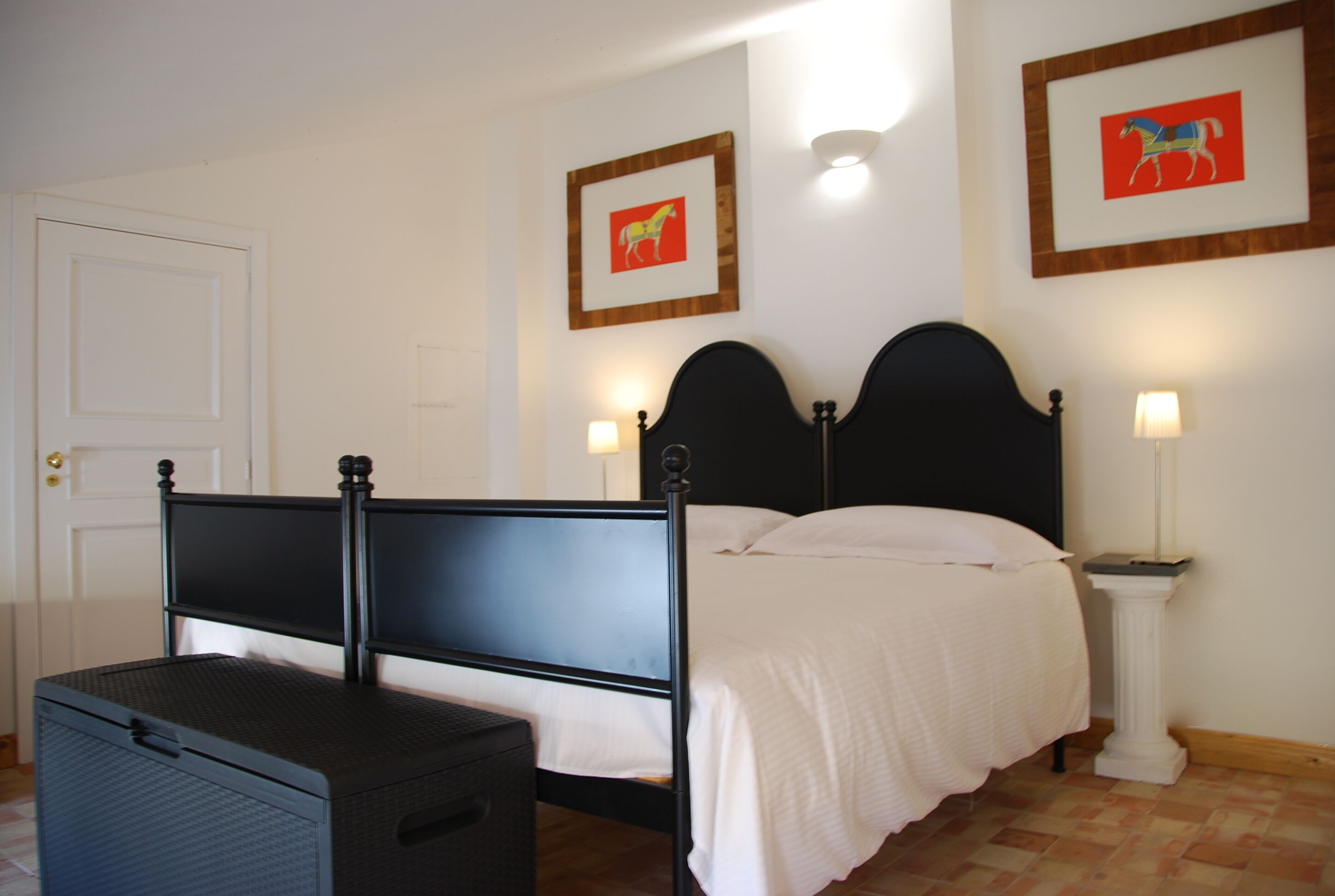 Une chambre à coucher avec un lit, une table de chevet, une lampe et une valise.