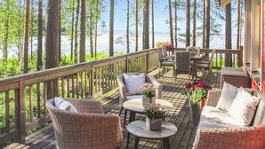 A wooden deck with wicker furniture, a table, and chairs overlooking a body of water.