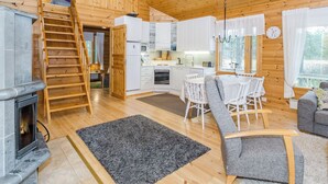 A wooden cabin interior with a kitchen, dining area, and a fireplace. - Sammonranta by Interhome (Lieksa)