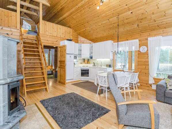 Ein Holzblockhaus-Innenraum mit Küche, Essbereich und Kamin.