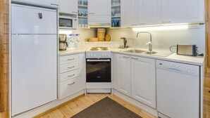 A compact kitchen with white cabinets, a built-in microwave, a stove, a sink, and a dishwasher. - Sammonranta by Interhome (Lieksa)