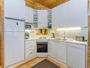 Een kleine keuken met witte kasten, een ingebouwde magnetron, een kookplaat, een spoelbak en een vaatwasser.