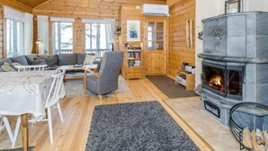 Un intérieur de chalet chaleureux avec une cheminée, des murs en bois, un canapé et un coin repas.