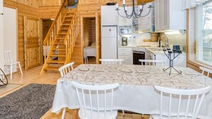 Un intérieur en bois comprenant une table à manger, des chaises, un escalier et un coin cuisine.