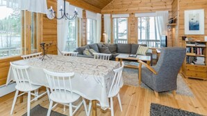 L’intérieur d’un chalet accueillant, avec une table à manger, des chaises, un canapé et une bibliothèque.
