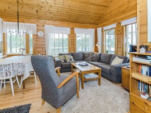 A cozy cabin interior with a dining area, a sofa set, a coffee table, and a bookshelf. - Sammonranta by Interhome (Lieksa)