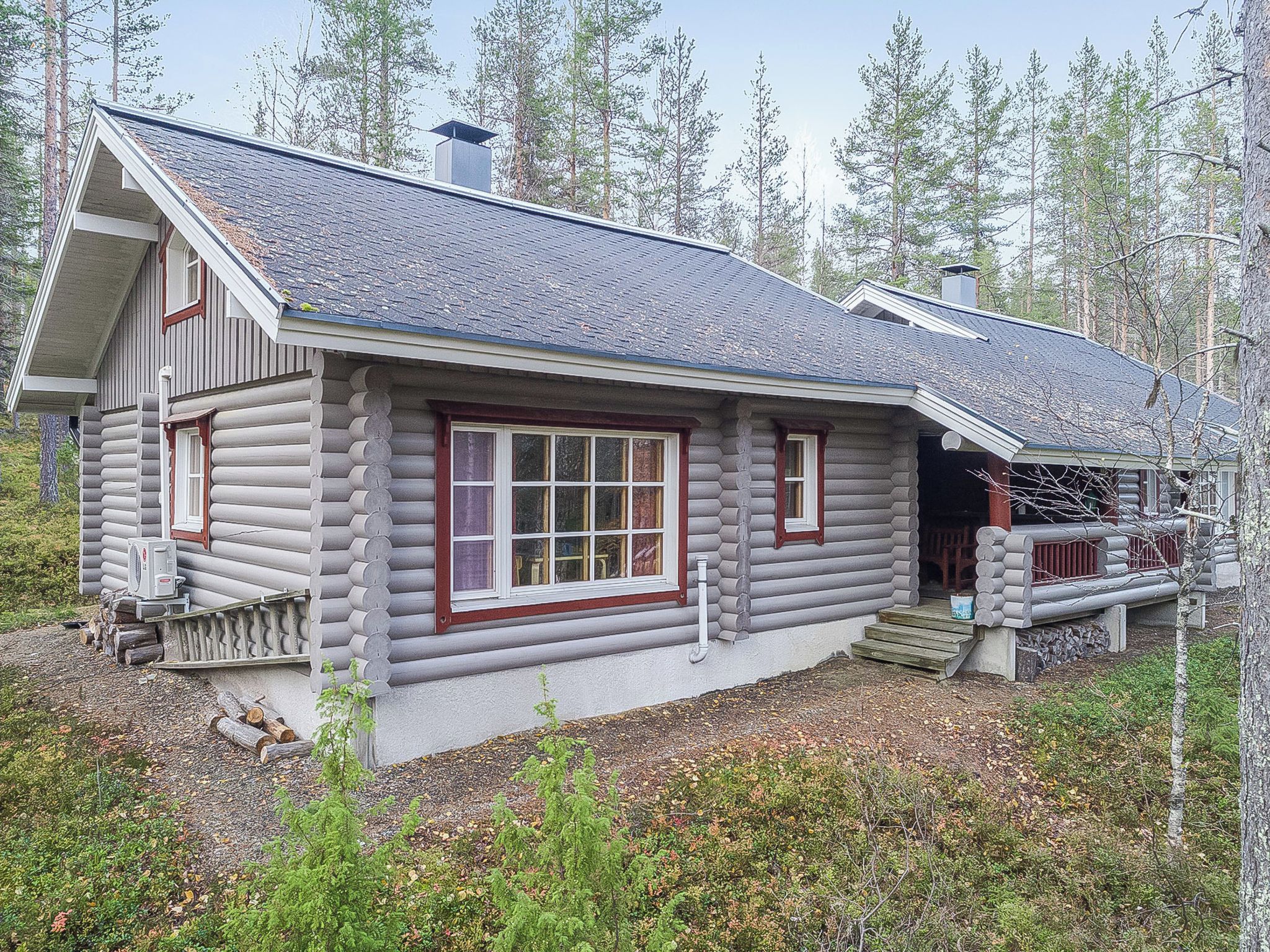 Une cabane en rondins dotée d’une grande fenêtre et d’un porche.
