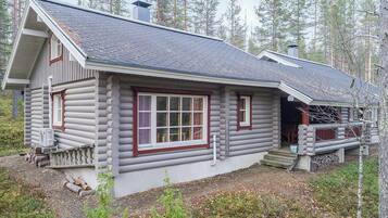 Une cabane en rondins dotée d’une grande fenêtre et d’un porche.