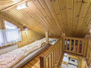Une cabine avec deux lits, une petite kitchenette et un balcon en bois.
