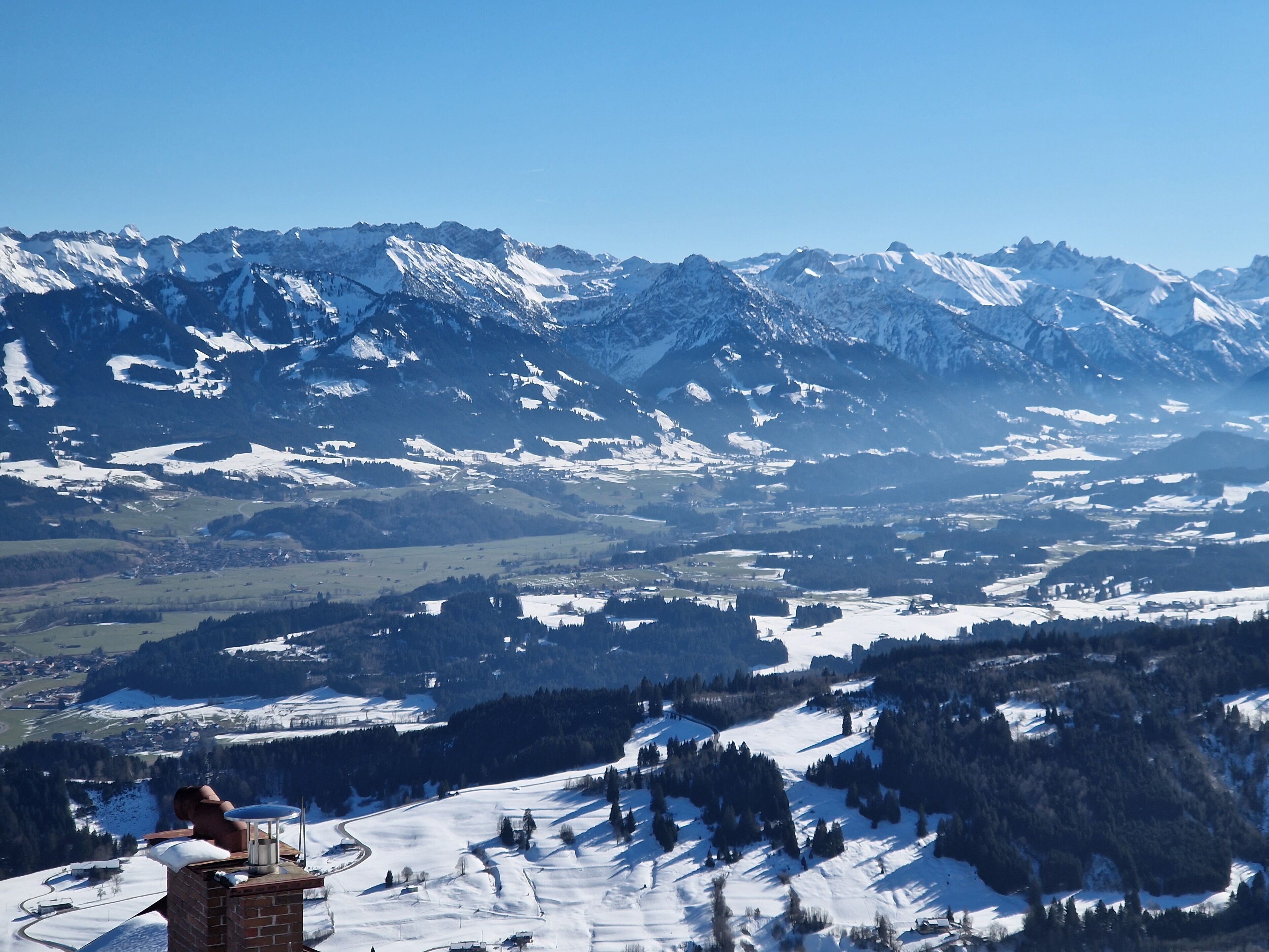 Ein Panoramablick auf eine Berglandschaft mit schneebedeckten Gipfeln und einem Tal.