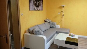 Una sala de estar con un sofá, una mesa de centro, una lámpara y un cuadro en la pared.