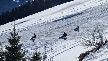 A snowy slope with three people sledding.