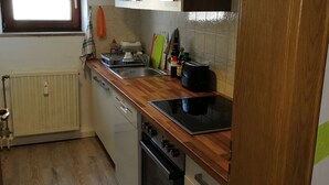 Una cocina con mostrador de madera, estufa, horno, ventana y radiador.
