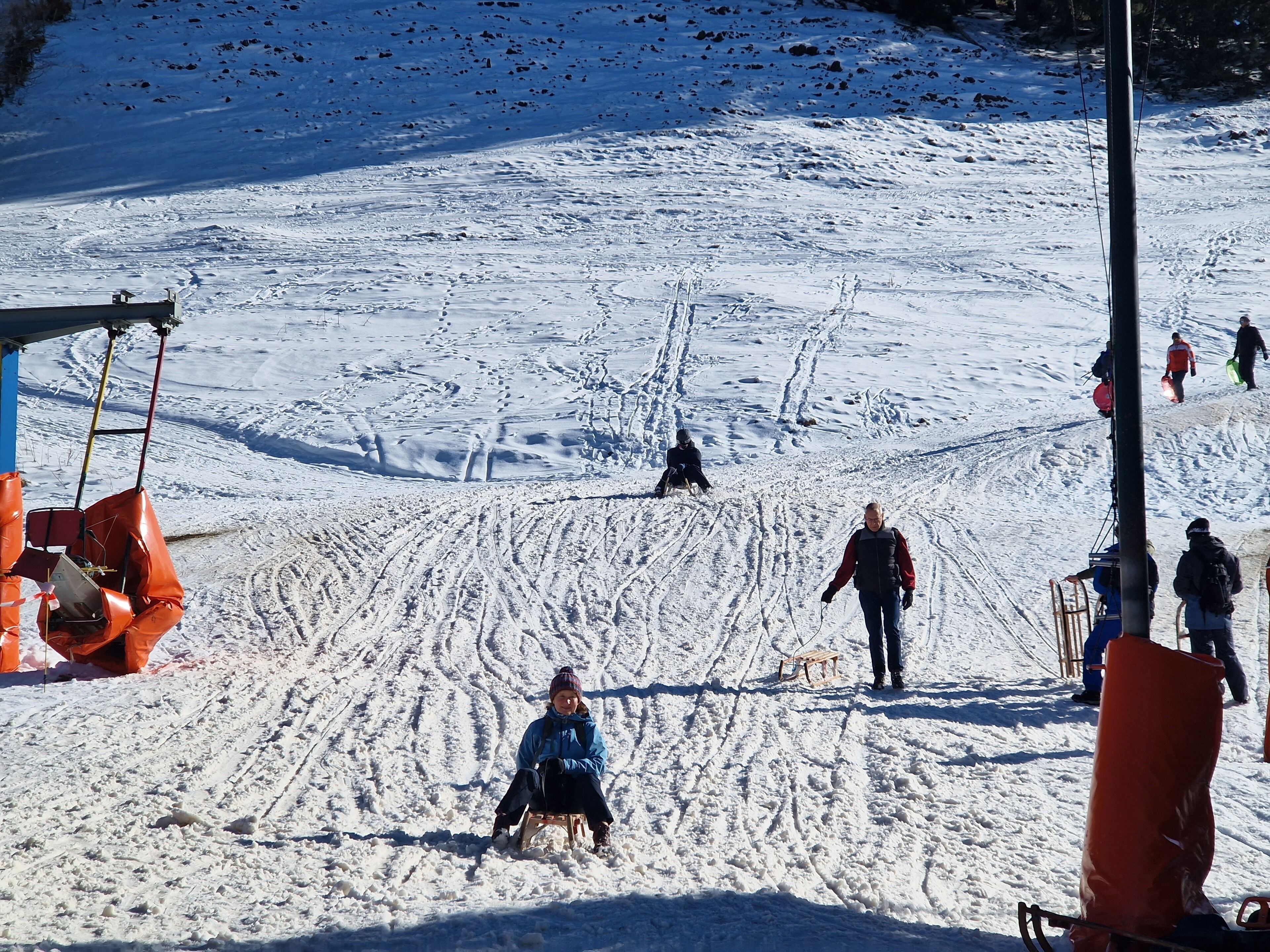 Ein verschneiter Skipisten mit Personen, die Ski fahren und Snowboarden.