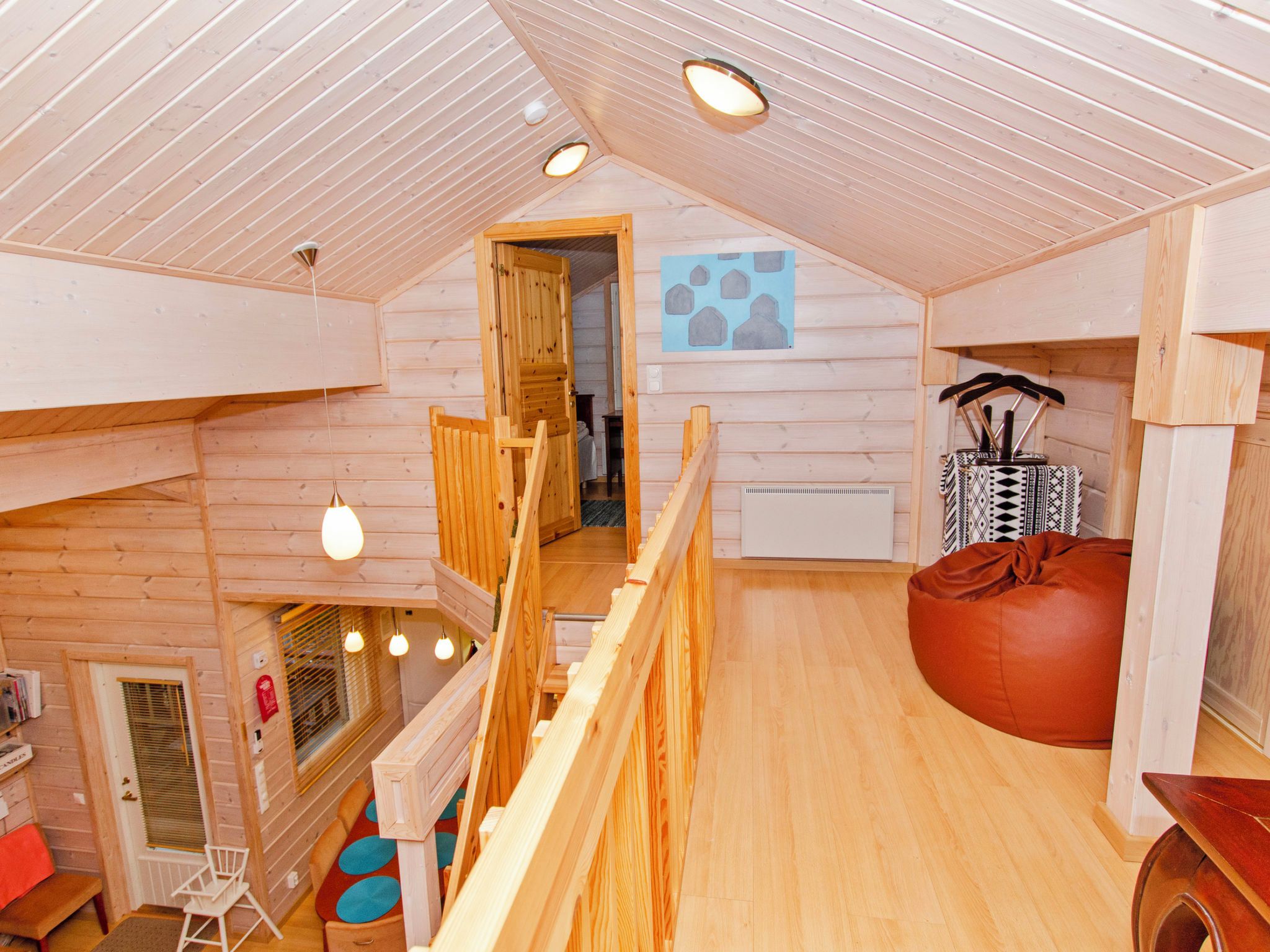 Ein Holzinnenraum mit Schlafzimmer im oberen Bereich, Essbereich und Blick ins Freie.