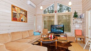 A cozy cabin interior with a sofa, a TV, and a wooden table.