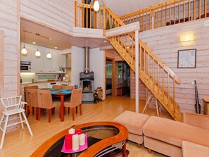 A spacious living area with a wooden staircase, a dining table with chairs, a sofa, and a coffee table with candles. - Otsopirtti, otso by Interhome (Lieksa)