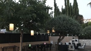 An outdoor patio with a long table and chairs, surrounded by trees and a stone wall. - Fabulous family friendly 4 bed villa with private pool (Alcaucín)