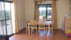 A dining area with a table and chairs, a chandelier, and a view through the window. - Fabulous family friendly 4 bed villa with private pool (Alcaucín)