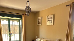 A bedroom with a bed, bedside tables, a chair, a window with curtains, and a hanging light fixture. - Fabulous family friendly 4 bed villa with private pool (Alcaucín)
