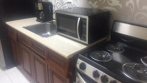Una cocina equipada con microondas, estufa y cafetera.