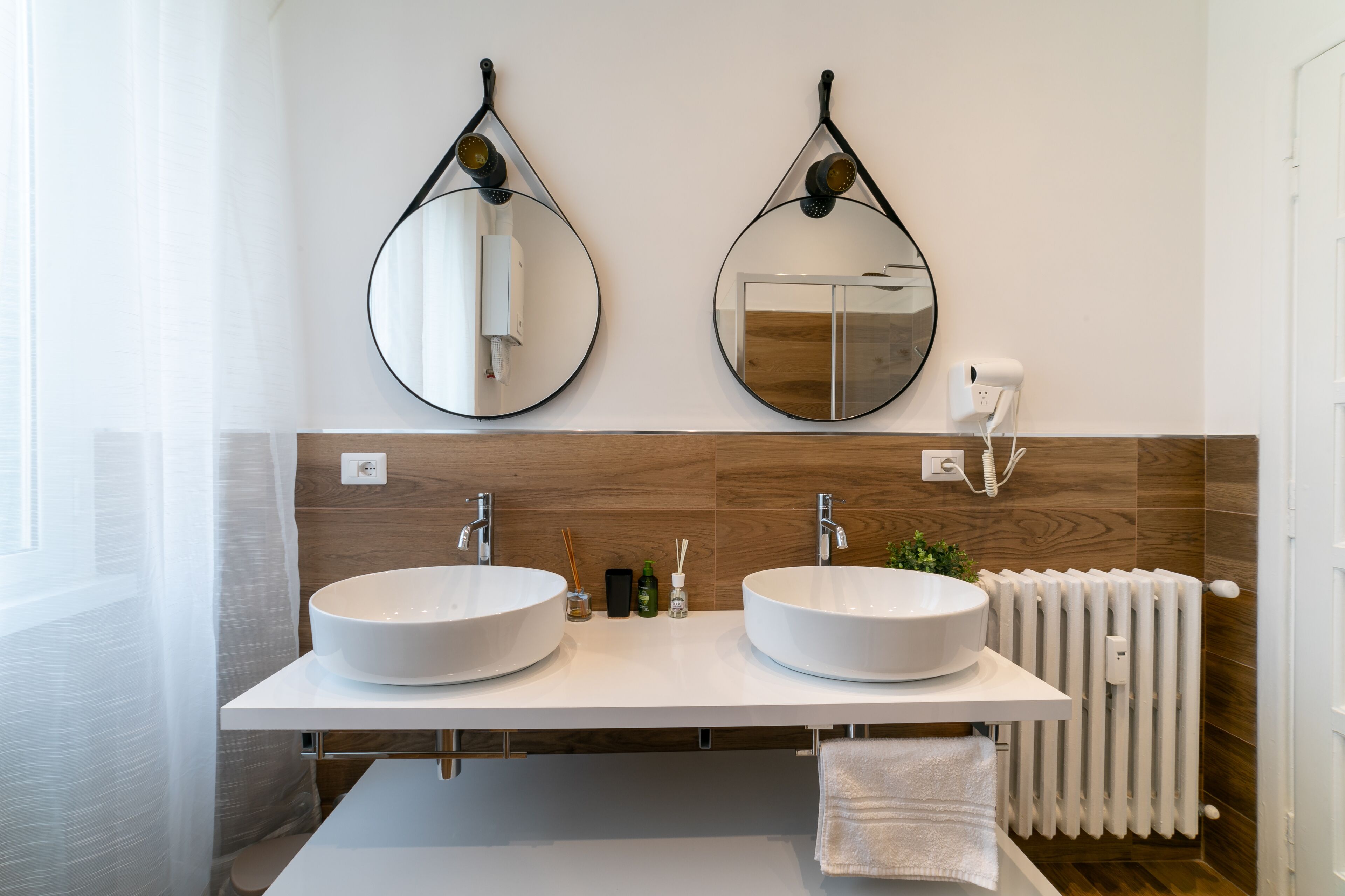 Ein modernes Badezimmer mit zwei großen, runden Waschbecken, einer weißen Arbeitsplatte und einer Holzvertäfelung.