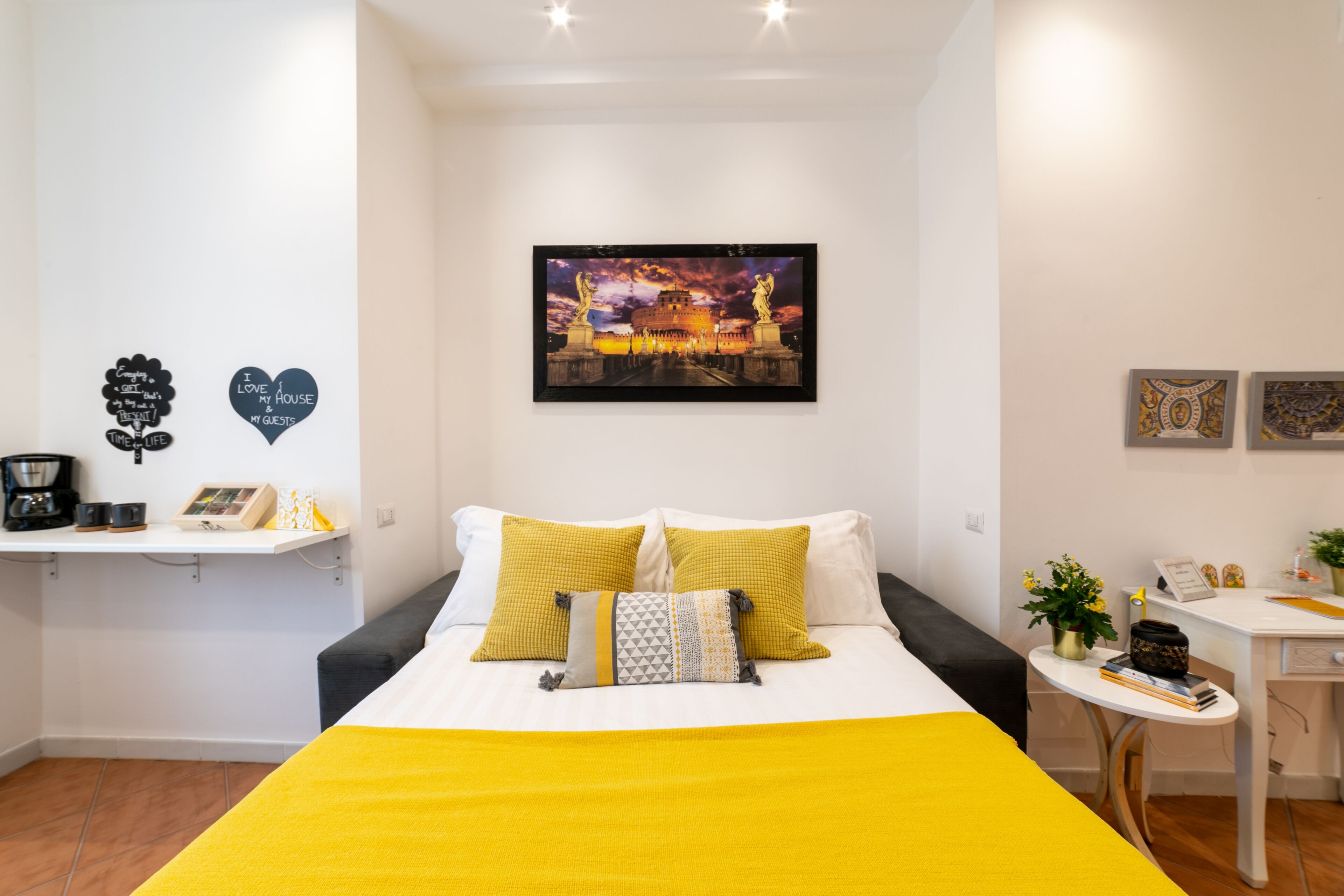 A neatly arranged hotel room with a bed, a small desk, and a wall-mounted picture.