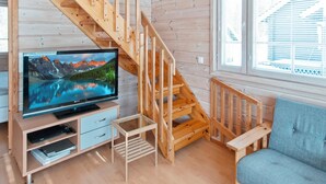 A wooden interior with a staircase, a television, and a window with blinds.