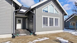 A two-story house with a grey exterior, a covered porch, and a sign reading "YLLAS-ROPO".
