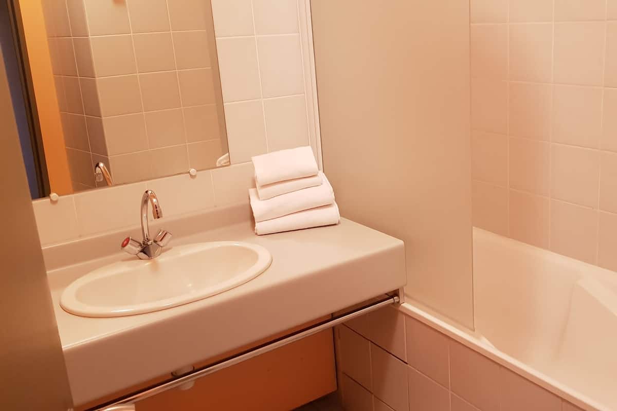 Ein Badezimmer mit Waschbecken, Spiegel und gestapelten Handtüchern.