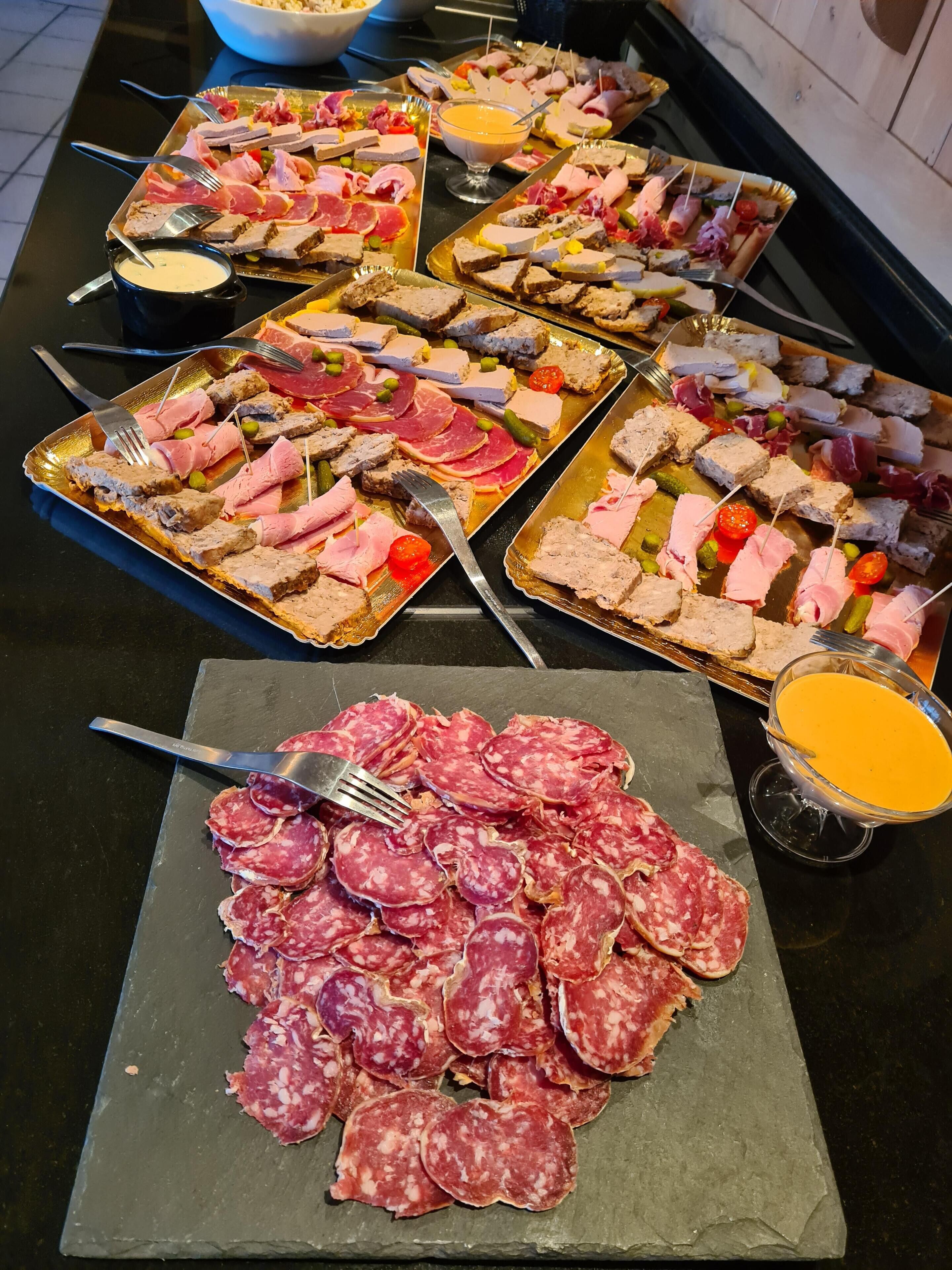 A buffet table with various types of meats and cheeses, including salami, ham, and different types of cheese, along with a bowl of soup.