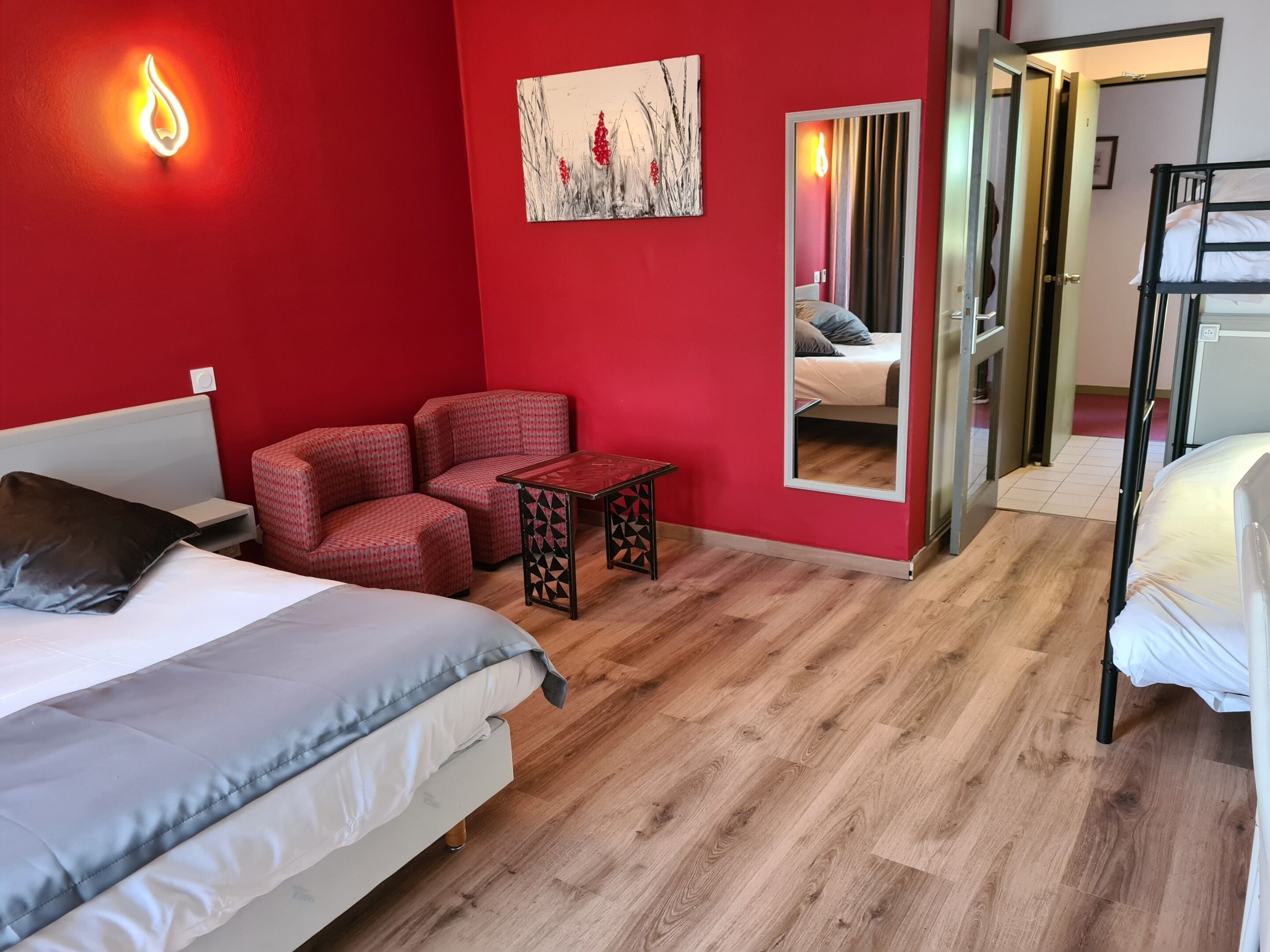 Een kamer met een bed, een stoel, een kleine tafel en een spiegel.