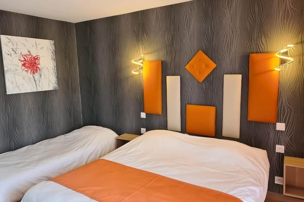 Ein Hotelzimmer mit zwei Betten, einer Holzpaneelausstattung, einem Gemälde einer roten Blume und modernen Wandleuchten.