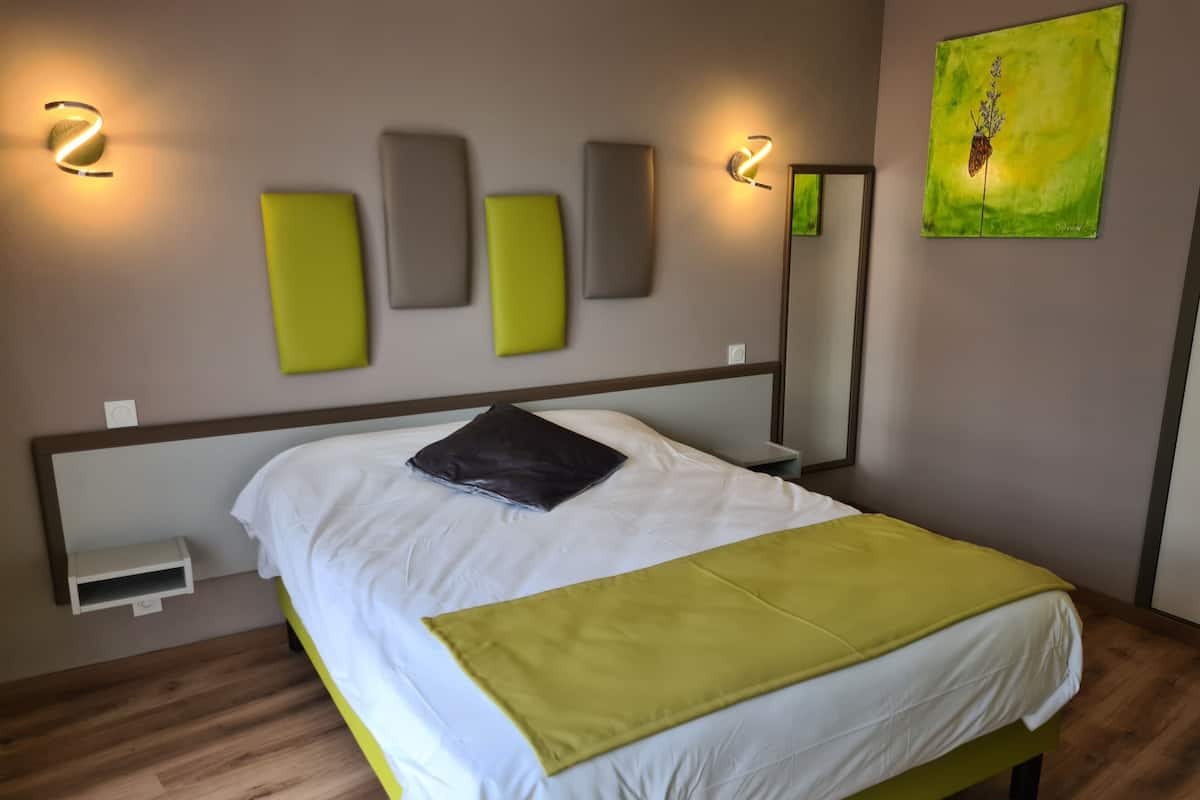 Ein modernes Hotelzimmer mit einem großen Bett, einem Nachttisch und einer Wandlampe.