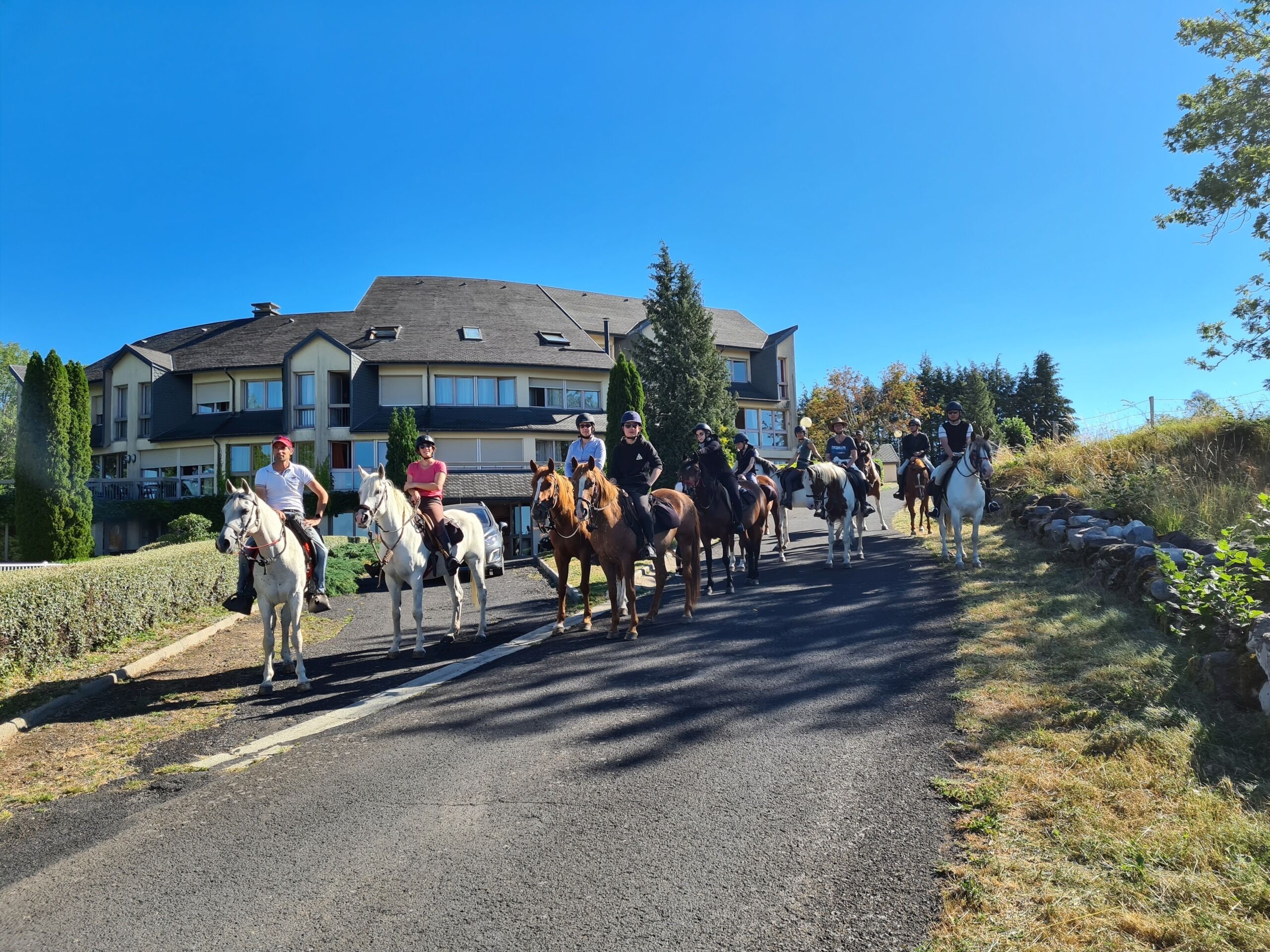 A group of people riding horses on a residential street.