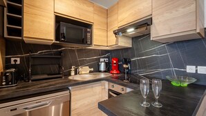 Una cocina moderna con armarios de madera, encimera negra, microondas integrado, cafetera y lavavajillas.