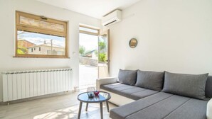 Una sala de estar moderna con un sofá gris, una mesita redonda y vistas al exterior a través de amplios ventanales.