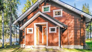 A log cabin with a gabled roof, a front door, and two windows.