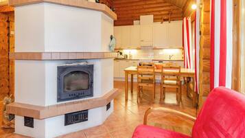 A cozy interior with a fireplace, wooden furniture, and a kitchen area.
