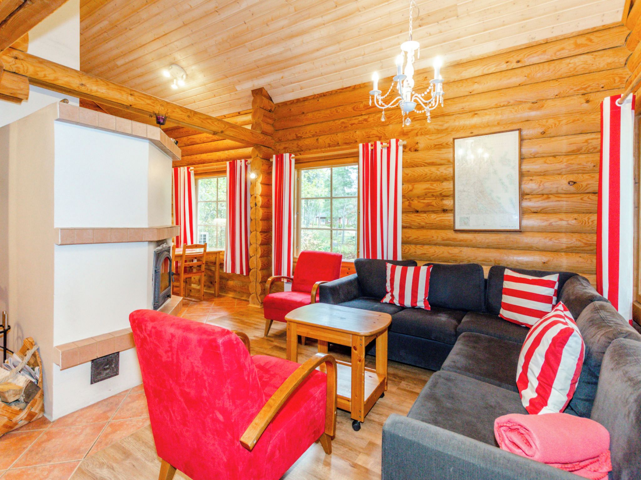 A log cabin interior with a fireplace, wooden furniture, and a chandelier.