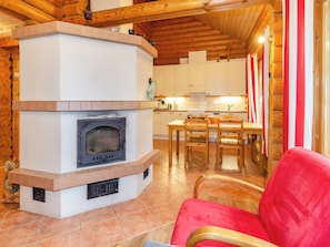 A cozy interior with a fireplace, wooden furniture, and a kitchen area.