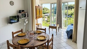 Een eethoek met een ronde tafel voor vier personen, een magnetron, een ventilator en een kast.