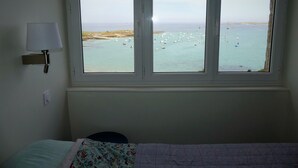 A bedroom with a large window overlooking a coastal area with boats. - Character house with 180° panoramic sea view - Côte Sauvage de Portsall (Landunvez)