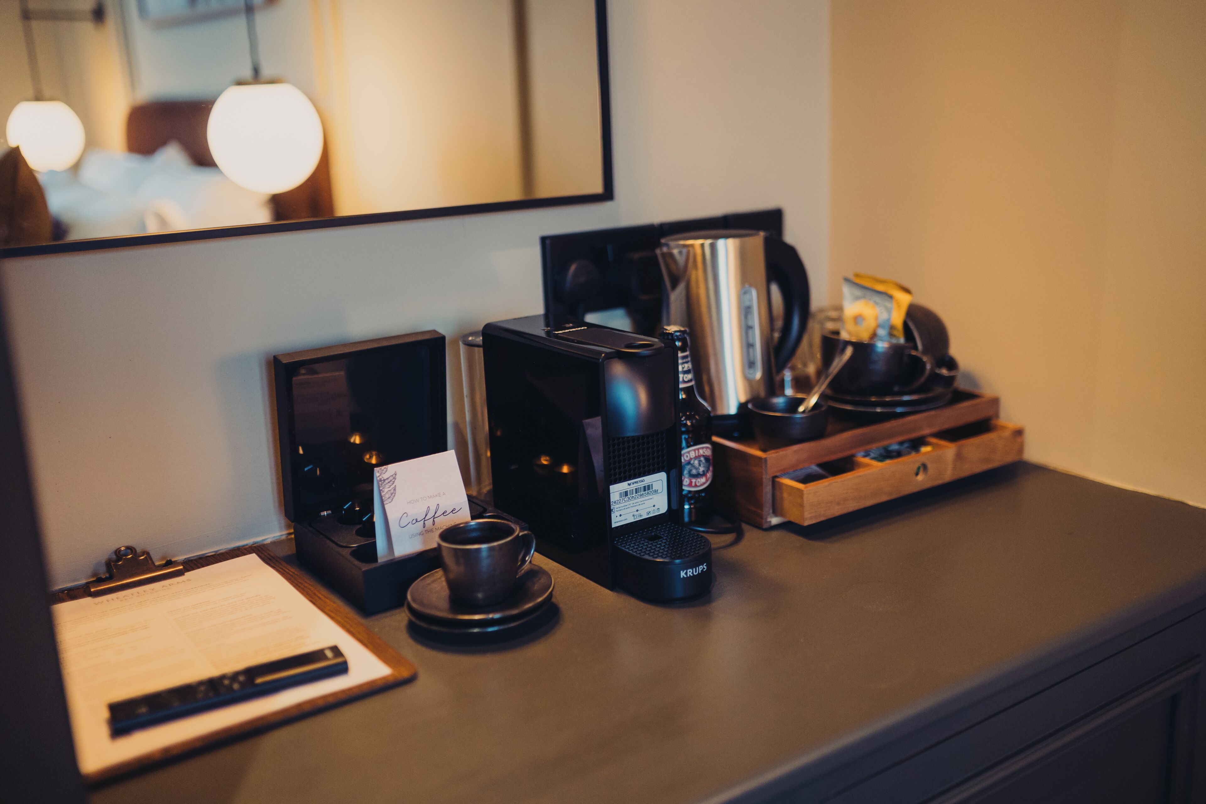 A coffee station with a coffee maker, a kettle, and a cup on a counter.