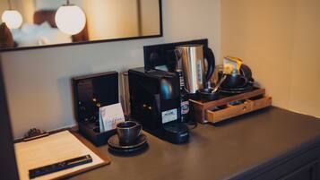 A coffee station with a coffee maker, a kettle, and a cup on a counter.